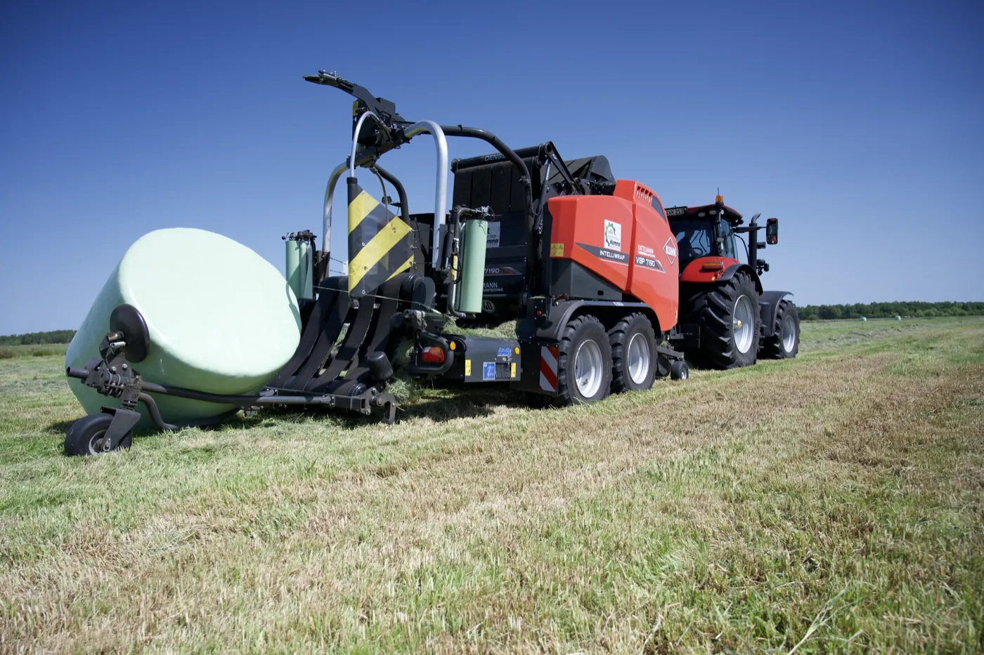 Presse legt einen fertig gewickelten Ballen auf dem Feld ab
