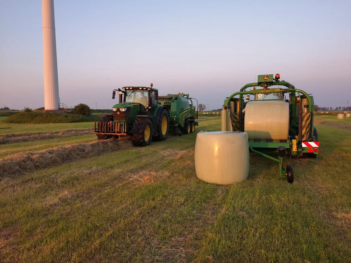 Traktor mit Press-Wickel-Gespann in der Abenddämmerung